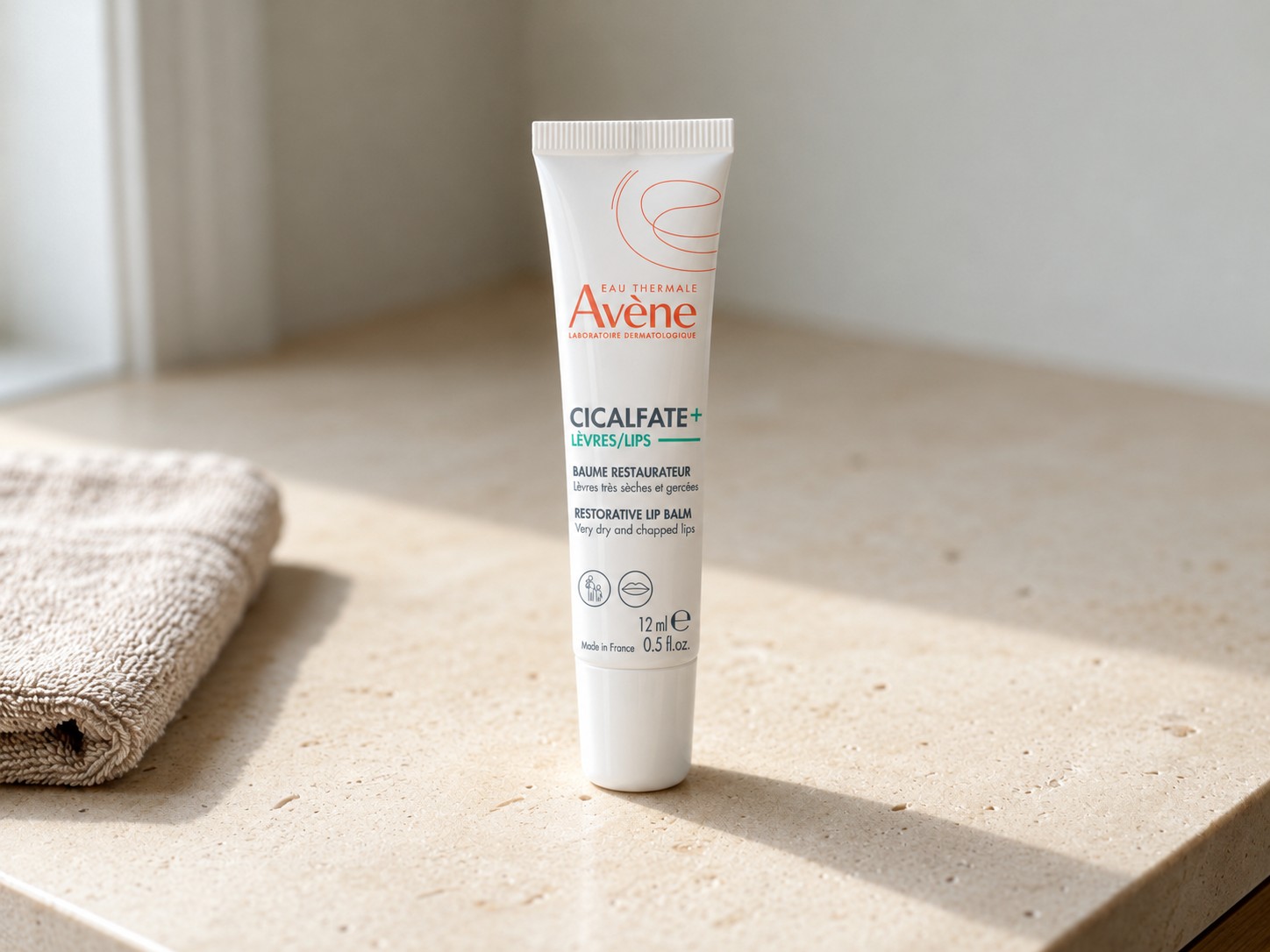 Avène Cicalfate+ LIPS Restorative Lip Balm on a warm stone vanity