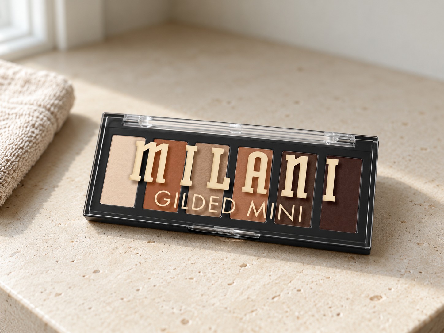 Milani Gilded Mini Eyeshadow Palette in Whiskey Business on a warm stone vanity