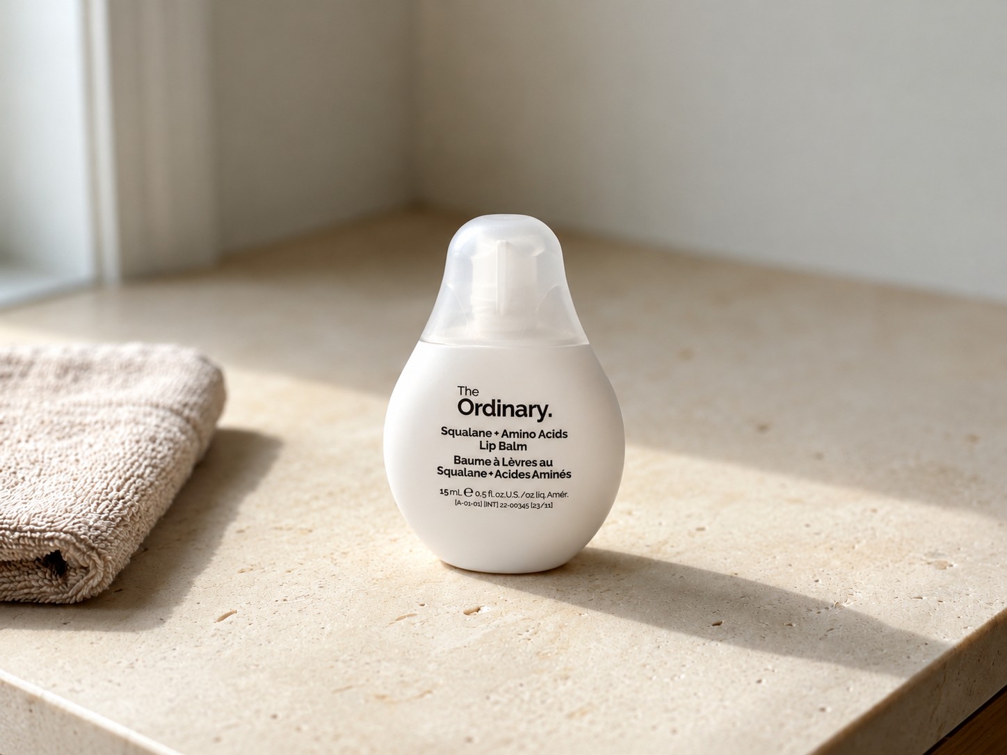 The Ordinary Squalane + Amino Acids Lip Balm on a warm stone vanity
